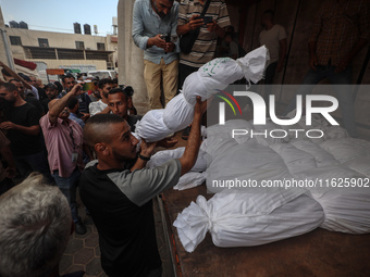 Relatives of Palestinians who are killed following the Israeli attack on the Nuseirat refugee camp mourn after the bodies are transferred to...