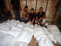 Relatives of Palestinians who are killed following the Israeli attack on the Nuseirat refugee camp mourn after the bodies are transferred to...