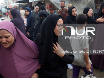 Relatives of Palestinians who are killed following the Israeli attack on the Nuseirat refugee camp mourn after the bodies are transferred to...