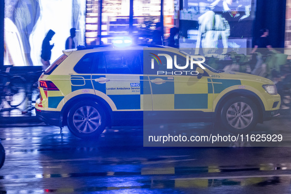 Ambulance in London. Emergency Services Ambulance Vehicle of NHS London Ambulance Service spotted during the night flashing blue light and u...