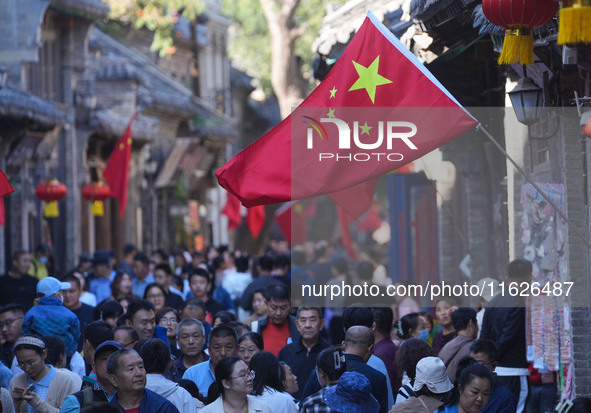 Tourists visit Zhoucun Ancient Shopping Mall decorated with red flags in Zibo, China, on October 1, 2024. 