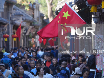 Tourists visit Zhoucun Ancient Shopping Mall decorated with red flags in Zibo, China, on October 1, 2024. (