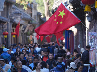 Tourists visit Zhoucun Ancient Shopping Mall decorated with red flags in Zibo, China, on October 1, 2024. (