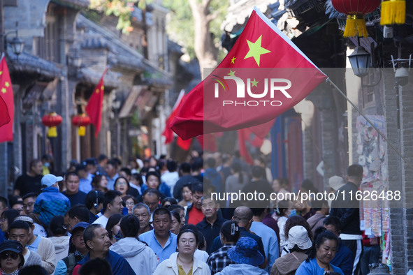 Tourists visit Zhoucun Ancient Shopping Mall decorated with red flags in Zibo, China, on October 1, 2024. 