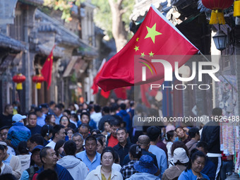 Tourists visit Zhoucun Ancient Shopping Mall decorated with red flags in Zibo, China, on October 1, 2024. (