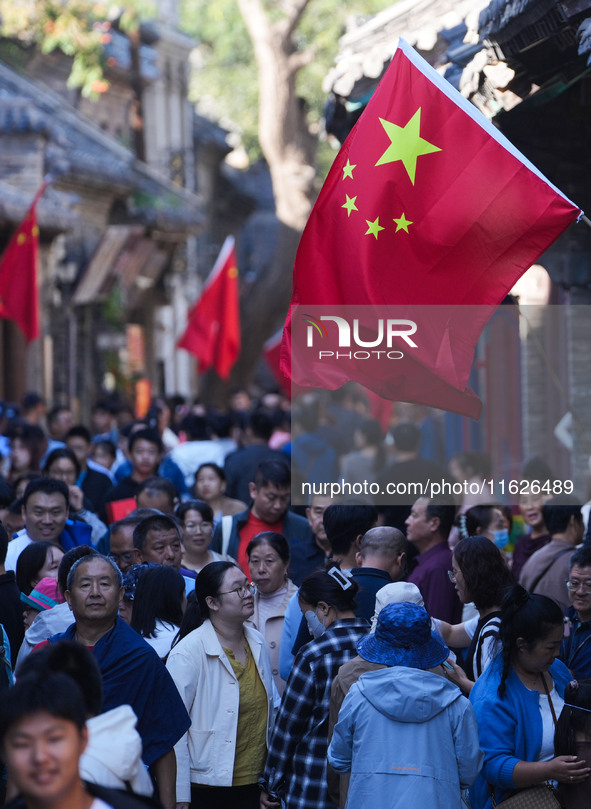 Tourists visit Zhoucun Ancient Shopping Mall decorated with red flags in Zibo, China, on October 1, 2024. 