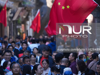 Tourists visit Zhoucun Ancient Shopping Mall decorated with red flags in Zibo, China, on October 1, 2024. (