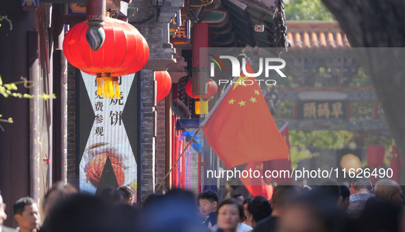 Tourists visit Zhoucun Ancient Shopping Mall decorated with red flags in Zibo, China, on October 1, 2024. 