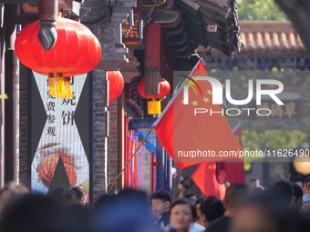 Tourists visit Zhoucun Ancient Shopping Mall decorated with red flags in Zibo, China, on October 1, 2024. (