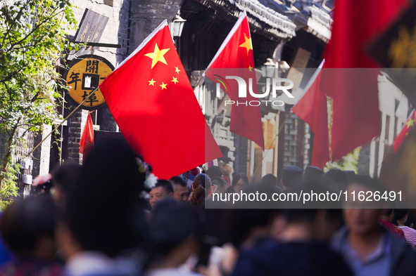 Tourists visit Zhoucun Ancient Shopping Mall decorated with red flags in Zibo, China, on October 1, 2024. 