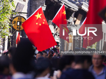 Tourists visit Zhoucun Ancient Shopping Mall decorated with red flags in Zibo, China, on October 1, 2024. (