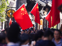 Tourists visit Zhoucun Ancient Shopping Mall decorated with red flags in Zibo, China, on October 1, 2024. (