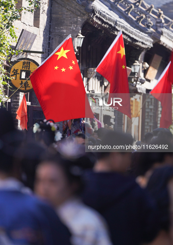 Tourists visit Zhoucun Ancient Shopping Mall decorated with red flags in Zibo, China, on October 1, 2024. 