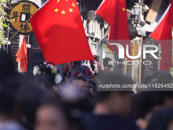 Tourists visit Zhoucun Ancient Shopping Mall decorated with red flags in Zibo, China, on October 1, 2024. (