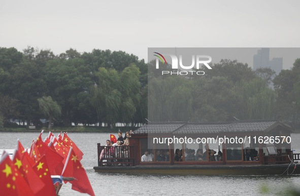 The five-star red flags fly in the wind on the West Lake cruise boat to celebrate the 75th anniversary of the founding of the People's Repub...