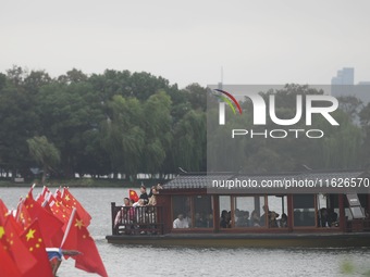 The five-star red flags fly in the wind on the West Lake cruise boat to celebrate the 75th anniversary of the founding of the People's Repub...