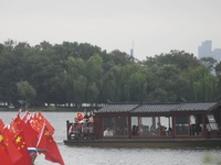 The five-star red flags fly in the wind on the West Lake cruise boat to celebrate the 75th anniversary of the founding of the People's Repub...