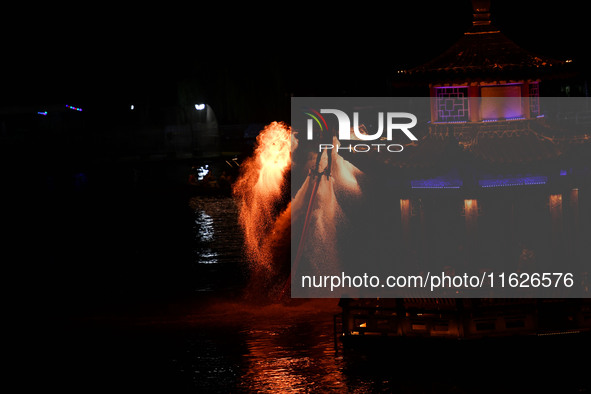 A folk artist dressed in fire-proof clothing puts burned charcoal into an iron net on both sides and shakes the net to create fireworks in F...