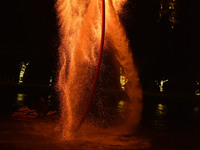 A folk artist dressed in fire-proof clothing puts burned charcoal into an iron net on both sides and shakes the net to create fireworks in F...