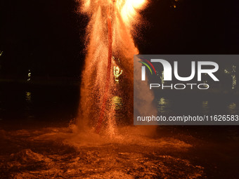 A folk artist dressed in fire-proof clothing puts burned charcoal into an iron net on both sides and shakes the net to create fireworks in F...