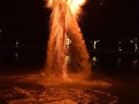 A folk artist dressed in fire-proof clothing puts burned charcoal into an iron net on both sides and shakes the net to create fireworks in F...