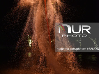 A folk artist dressed in fire-proof clothing puts burned charcoal into an iron net on both sides and shakes the net to create fireworks in F...