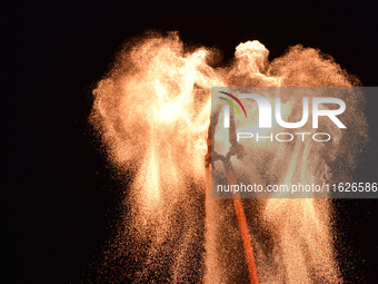 A folk artist dressed in fire-proof clothing puts burned charcoal into an iron net on both sides and shakes the net to create fireworks in F...