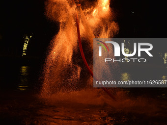 A folk artist dressed in fire-proof clothing puts burned charcoal into an iron net on both sides and shakes the net to create fireworks in F...