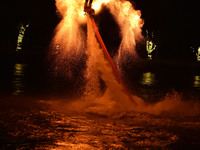 A folk artist dressed in fire-proof clothing puts burned charcoal into an iron net on both sides and shakes the net to create fireworks in F...