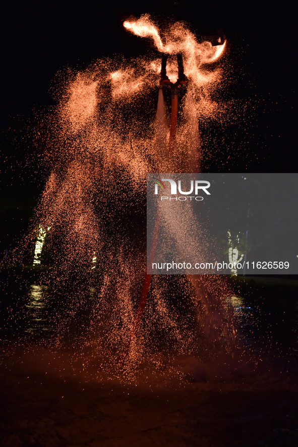 A folk artist dressed in fire-proof clothing puts burned charcoal into an iron net on both sides and shakes the net to create fireworks in F...