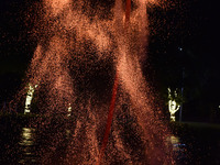 A folk artist dressed in fire-proof clothing puts burned charcoal into an iron net on both sides and shakes the net to create fireworks in F...