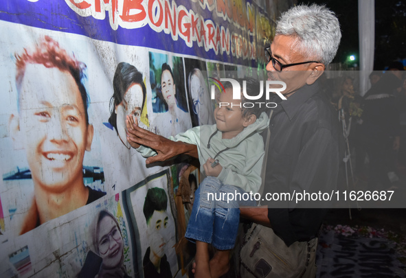 A child holds a poster of his mother with his grandfather during a prayer vigil to mark the second anniversary of the football disaster that...