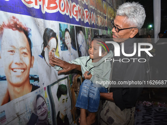 A child holds a poster of his mother with his grandfather during a prayer vigil to mark the second anniversary of the football disaster that...