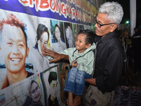 A child holds a poster of his mother with his grandfather during a prayer vigil to mark the second anniversary of the football disaster that...