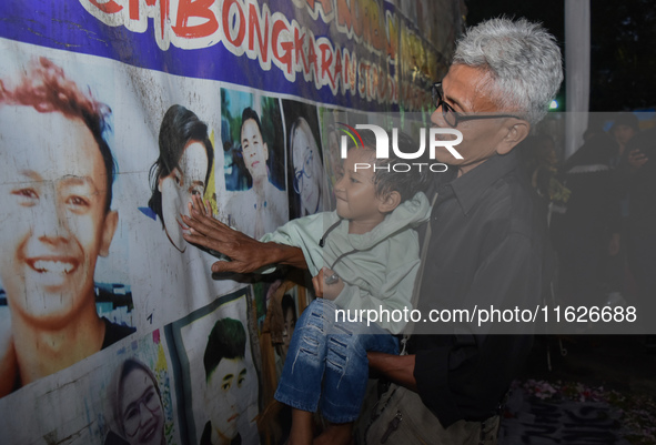 A child holds a poster of his mother with his grandfather during a prayer vigil to mark the second anniversary of the football disaster that...