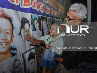 A child holds a poster of his mother with his grandfather during a prayer vigil to mark the second anniversary of the football disaster that...