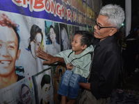 A child holds a poster of his mother with his grandfather during a prayer vigil to mark the second anniversary of the football disaster that...