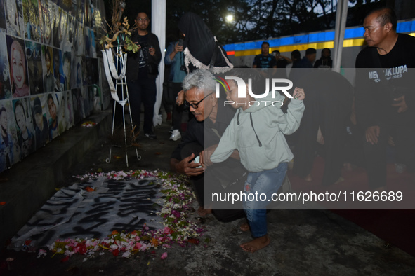 A child holds a poster of his mother with his grandfather during a prayer vigil to mark the second anniversary of the football disaster that...