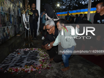 A child holds a poster of his mother with his grandfather during a prayer vigil to mark the second anniversary of the football disaster that...