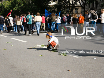 A child plays with leaves in a procession of the demonstration against the policies of Michel Barnier and Emmanuel Macron, in Paris, France,...