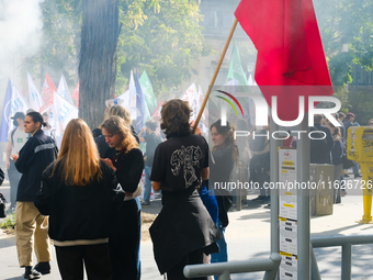 Young demonstrators with a red flag during the interprofessional strike day against the policies of Michel Barnier and Emmanuel Macron, in P...