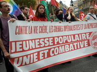 The banner reads 'against costly life, imperialist wars and crackdowns, popular youths united and fighting'. Between 3,000 and 5,000 protest...