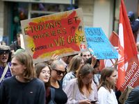 A protester holds a cardboard sign reading 'students and workers united against a costly life'. Between 3,000 and 5,000 protesters march in...