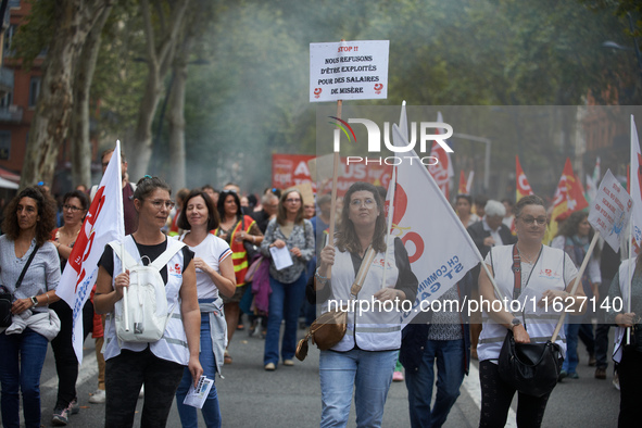 A woman walks with a placard reading 'Stop! We refuse to be exploited for a starvation salary'. Between 3,000 and 5,000 protesters march in...