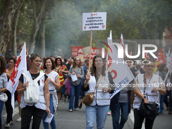 A woman walks with a placard reading 'Stop! We refuse to be exploited for a starvation salary'. Between 3,000 and 5,000 protesters march in...