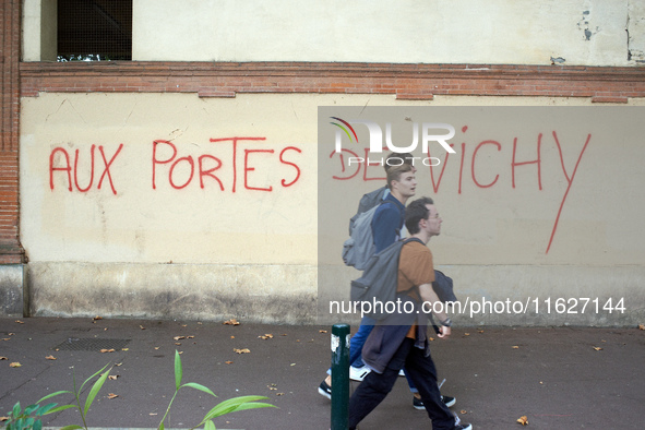 Youths walk in front of graffiti reading 'at the doors of Vichy'. Vichy is the only far-right government in France during WWII. Between 3,00...