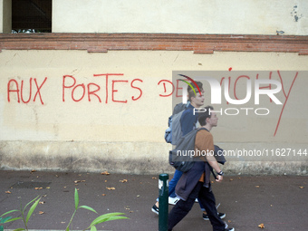 Youths walk in front of graffiti reading 'at the doors of Vichy'. Vichy is the only far-right government in France during WWII. Between 3,00...