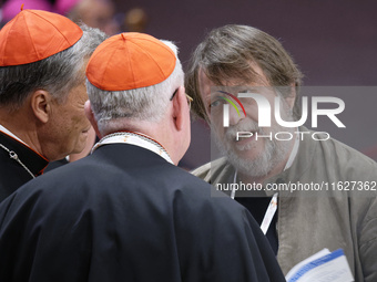 Luca Casarini, head of Mission of Mediterranea Saving Humans, talks with two cardinals before the vigil prayer in St. Peter's Basilica ahead...