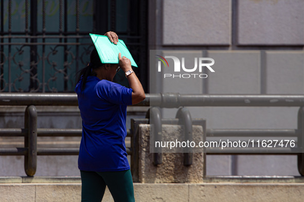 Pedestrians protect themselves from the intense heat in the central region of Sao Paulo, Brazil, on October 1, 2024. 