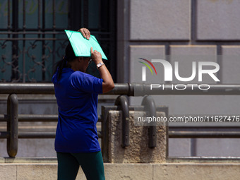 Pedestrians protect themselves from the intense heat in the central region of Sao Paulo, Brazil, on October 1, 2024. (